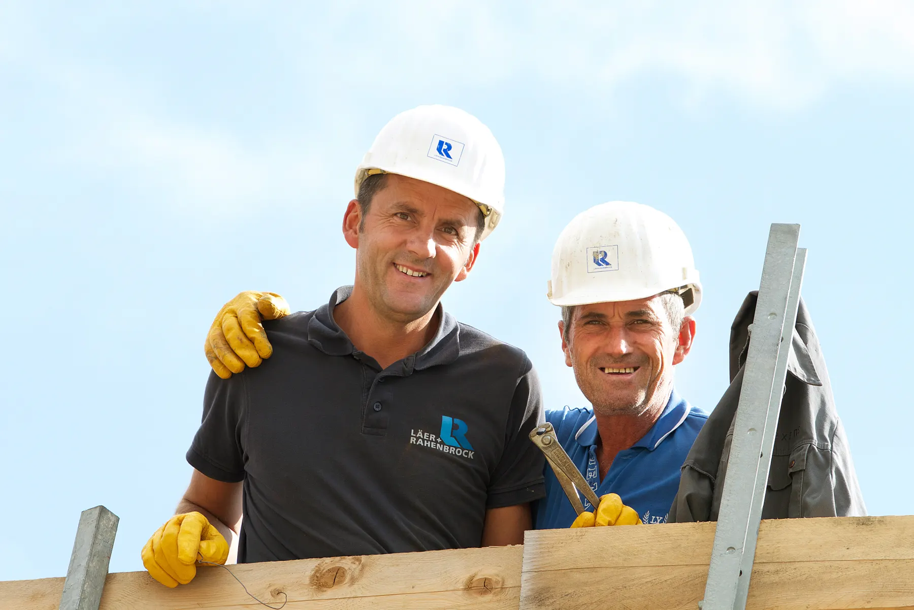 Zwei Mitarbeiter von Läer und Rahenbrock auf der Baustelle vor blauem Himmel