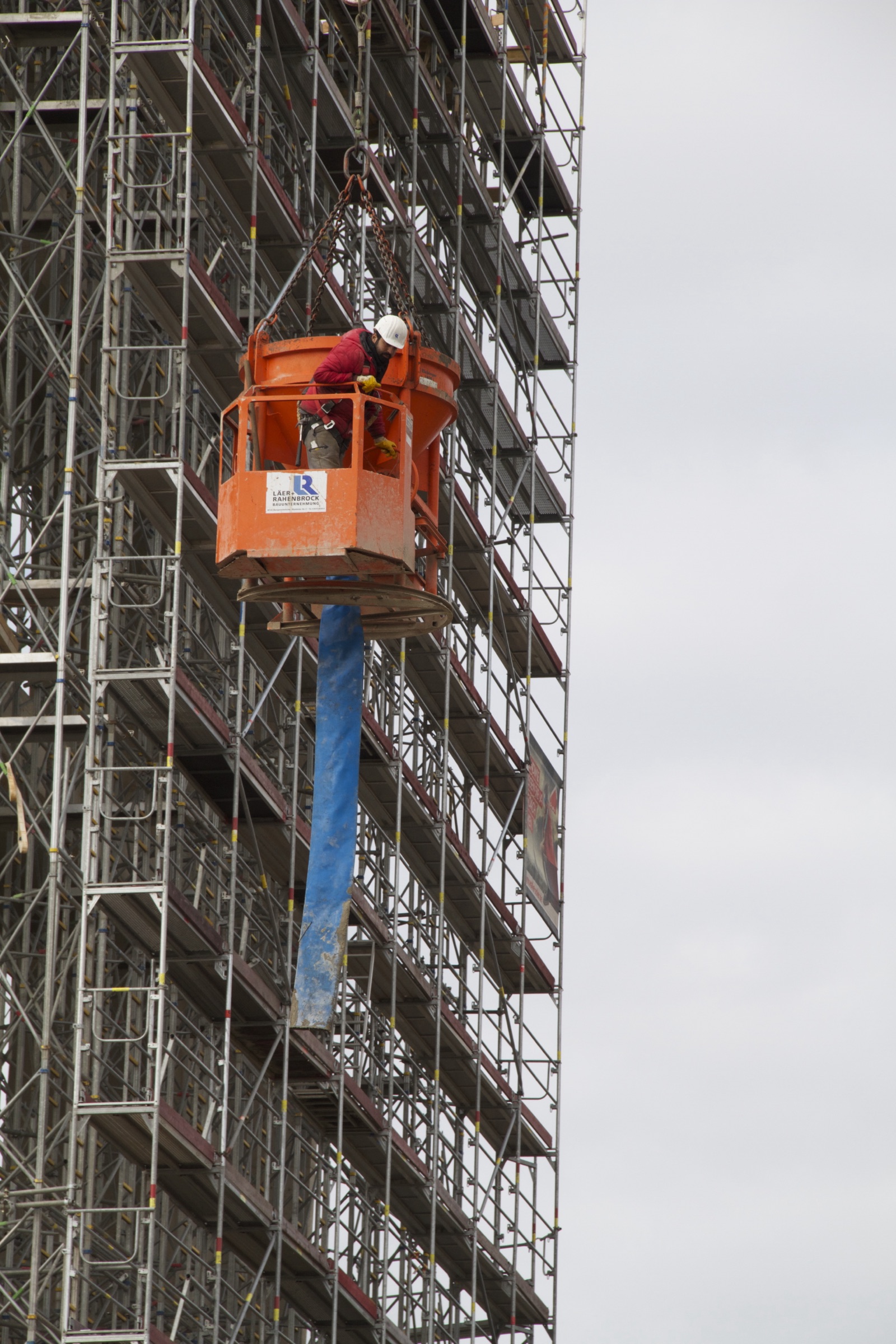 Arbeiter im Krankorb an einer eingerüsteten Fassade
